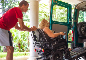 caregiver assisting patient on a wheelchair to get in the car