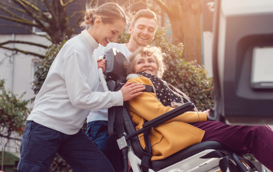 caregivers and elderly woman with wheelchair smiling