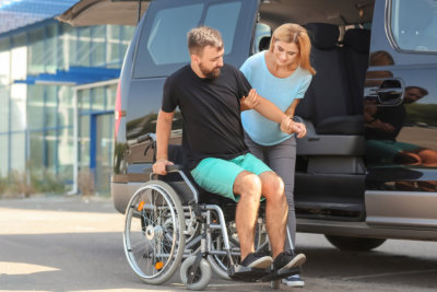  Woman helping handicapped man to sit in car